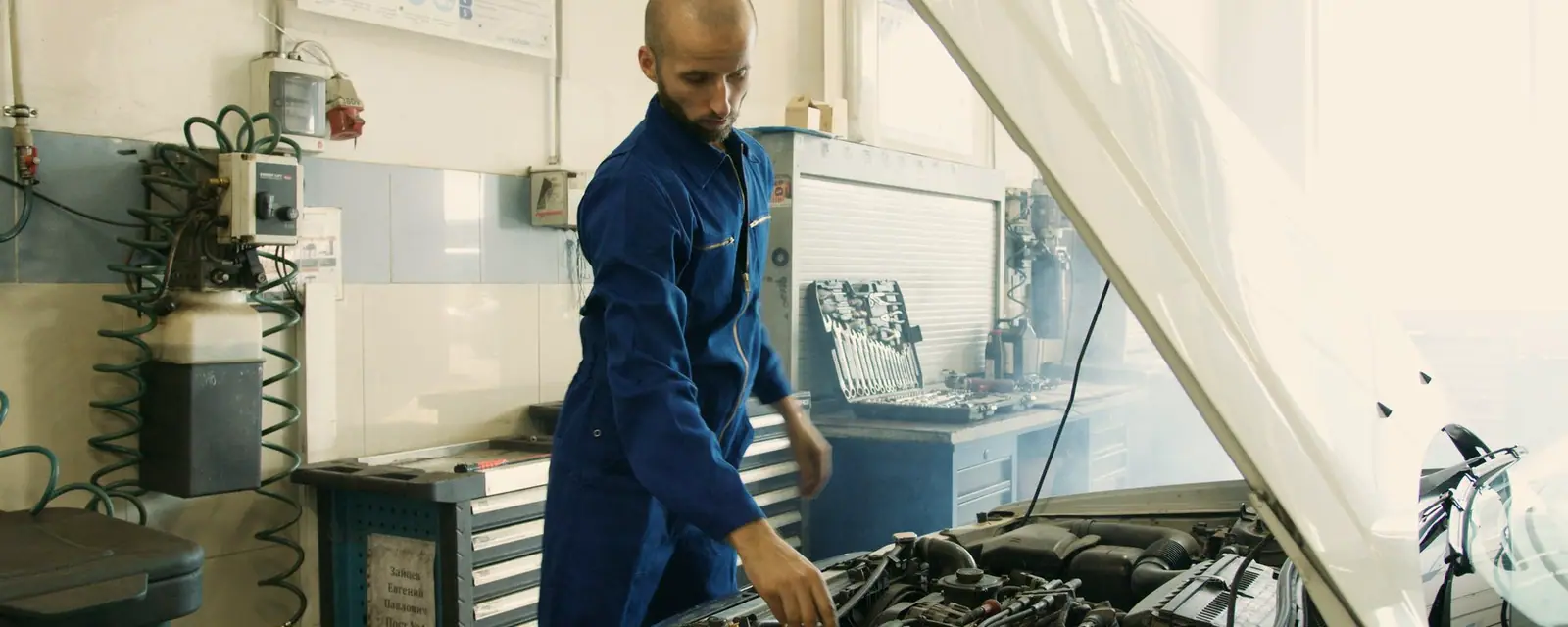 A mechanic inspecting a car with the hood raised